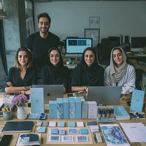 گروه جوانان استارتاپی پشت میز کار با لپ‌تاپ و محصولات برند خود در دفتر کار مدرن