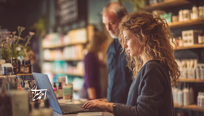 مدیر یک فروشگاه آرایشی که پشت لپ‌تاپ در حال تحلیل داده‌های فروش است؛ نمونه‌ای از استفاده از ستاره شمالی فروش (NSP) برای برنامه‌ریزی خرید، انبار و بهبود تجربه مشتری.