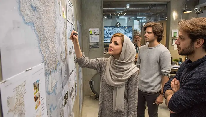 فريق عمل يخطط لاستراتيجية العلامة التجارية في إيران أمام خريطة كبيرة داخل مكتب حديث