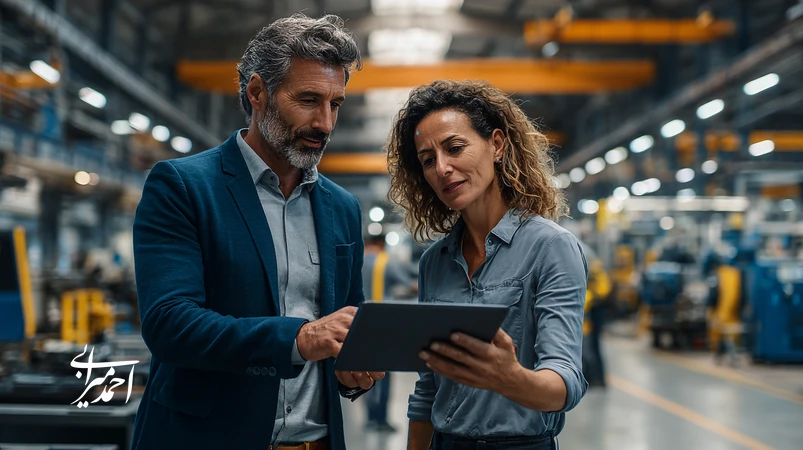 industrial coach and factory manager reviewing performance data on production floor, illustrating how coaching transforms leadership style and improves productivity in Iranian manufacturing