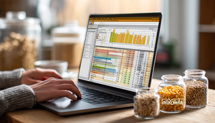 لپ‌تاپ با نمودارها و جدول‌های اکسل کنار شیشه‌های ذرت و غلات؛ پایش داده و قیمت نهاده‌ها در دانش‌دانه