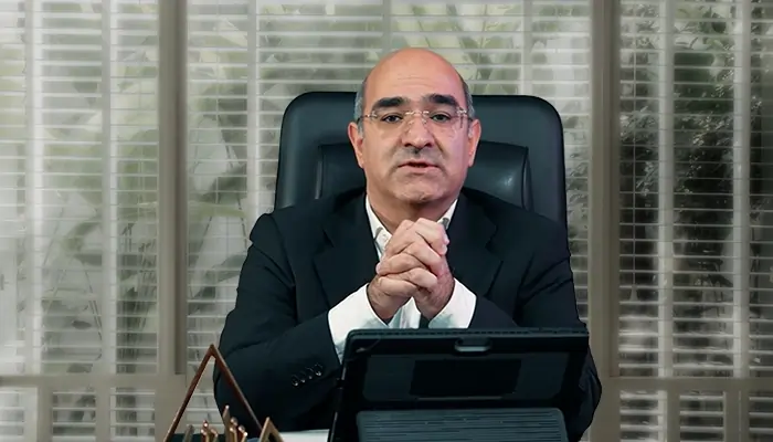 Доктор Ахмад Мираби — консультант по брендингу и развитию бизнеса, сидящий за рабочим столом в офисе, с сосредоточенным и уверенным выражением лица, в формальной деловой обстановке.