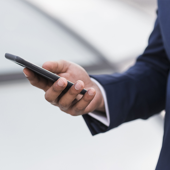 Рука делового человека, держащего смартфон, символизирующая цифровую коммуникацию и принятие бизнес-решений.