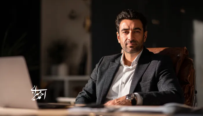 مدیر و کارآفرین ایرانی نشسته پشت میز کار در دفتر شخصی، با ظاهری حرفهای و تمرکز بر رهبری، تصمیمسازی و برند شخصی