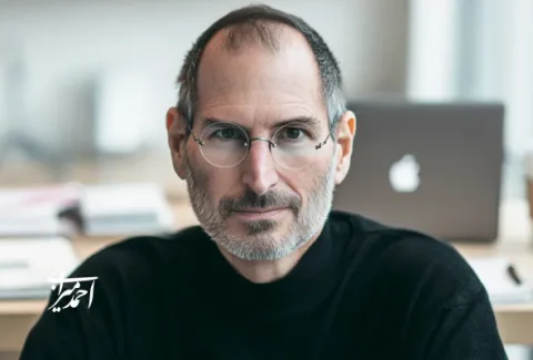 پرتره مردی شبیه استیو جابز با یقه‌اسکی مشکی پشت میز کار، با لپ‌تاپ و لیوان قهوه در پس‌زمینه؛ تصویر نماد نقد اسطوره‌سازی مدیریتی و تأکید بر تصمیم‌گیری سیستم‌محور در فرهنگ استارتاپی.