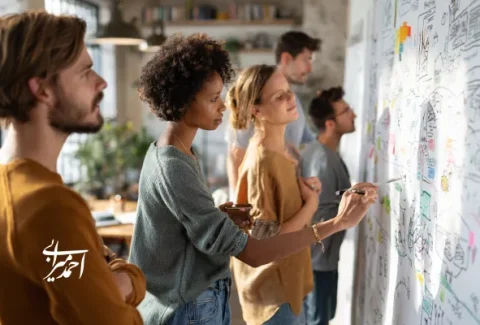 تیم حرفه‌ای در حال بررسی و طراحی نقشه تجربه گردشگر و استراتژی رشد کسب‌وکار گردشگری روی وایت‌برد در فضای کاری مدرن